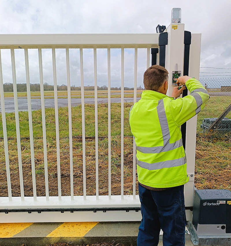 Technicien poseur automaticien travaillant sur un portail sur rail automatisé